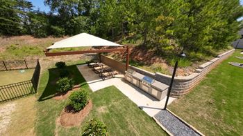a backyard with a stone retaining wall and a patio with a pergola